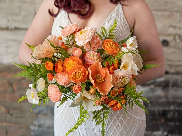 Bride holding a bunch of orange flowers