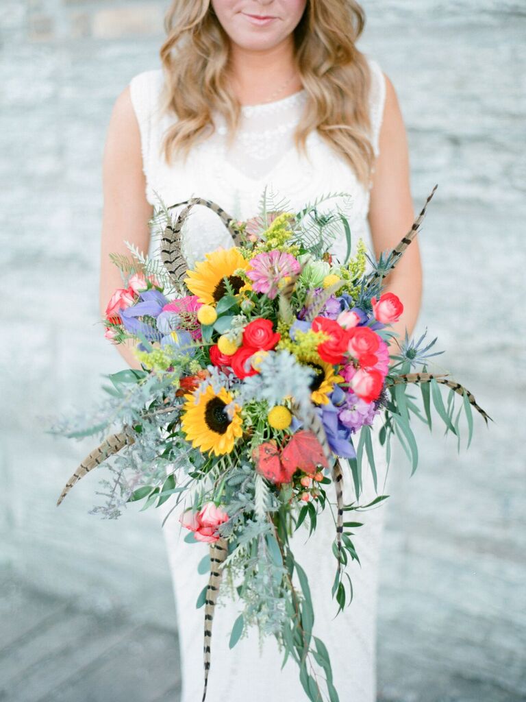 Bride holding bouquet with sunflowers and feathers