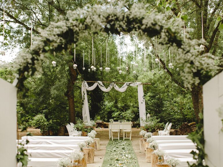 Civil ceremony Lisbon, Portugal wedding venue among trees, with white flowers and green foliage, and tea lights hanging from the trees.