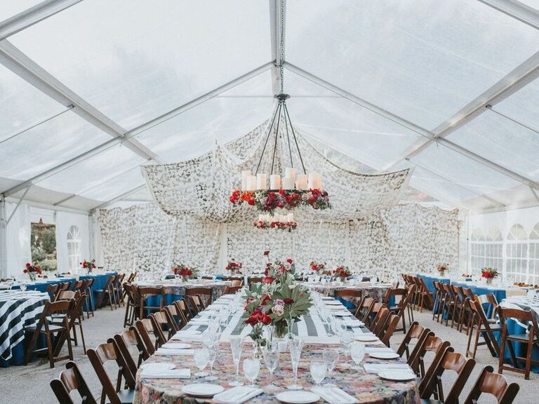 Wedding reception inside a clear enclosed event tent with a hanging chandleier and decor