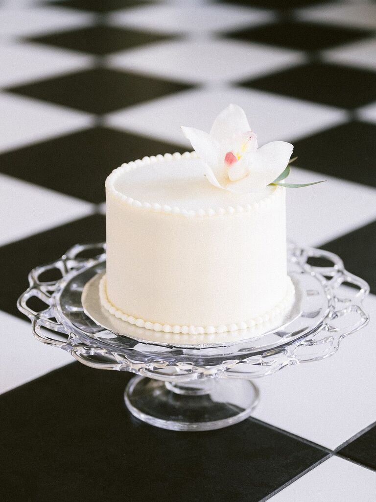 Simple one-tier white wedding cake on glass cake stand