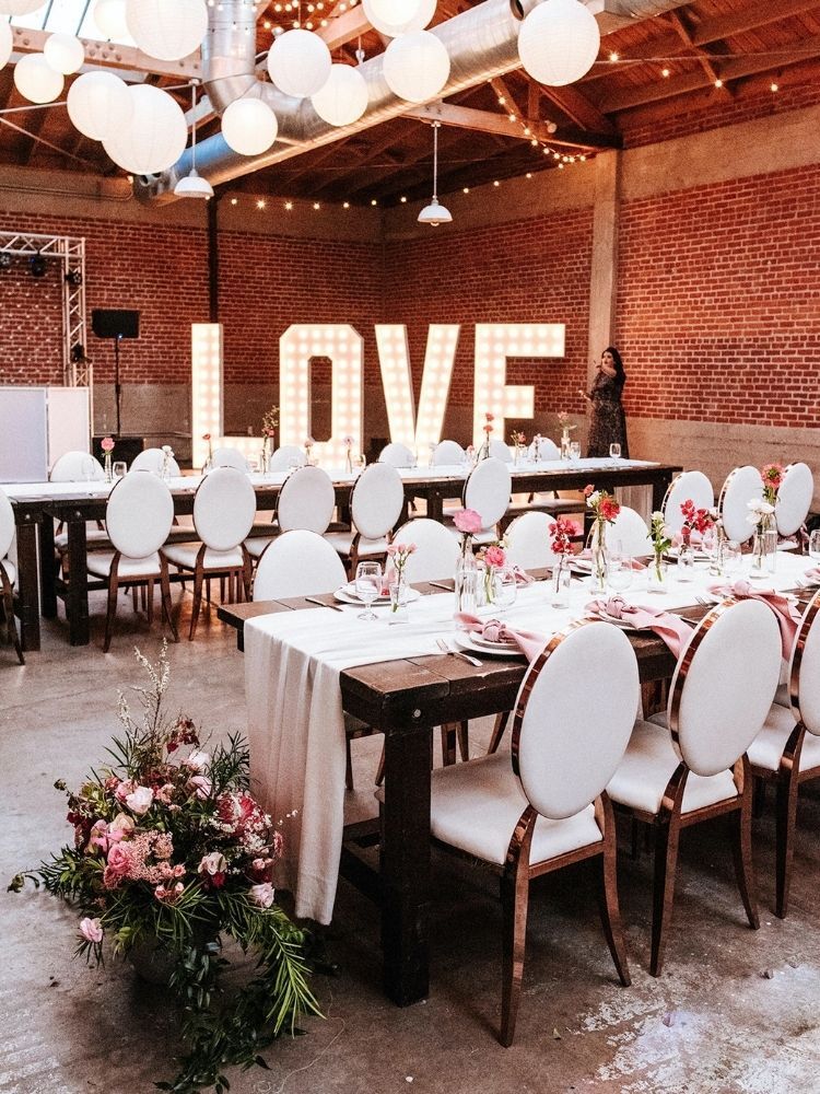 Modern wedding reception with white chairs, paper lanterns and marquee lights