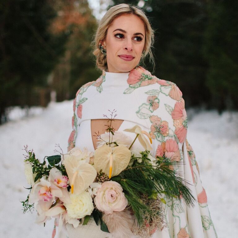bride holding winter wedding bouquet outside in the snow