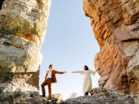 Couple's wedding portraits standing on rock reaching for each others hands, how to get married in Arizona