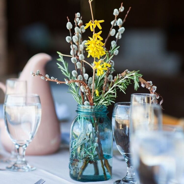 blue mason jar filled with pussy willow and yellow forsythia