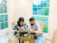 Couple sitting at kitchen table writing vendor review on laptop