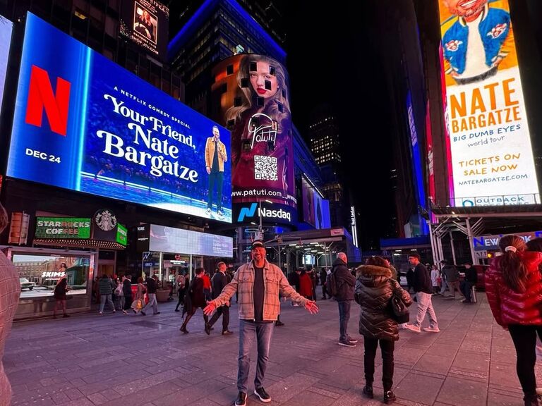 Nate Bargatze standing in front of two of his billboards 