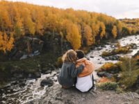 Couple sitting on rock together overlooking river