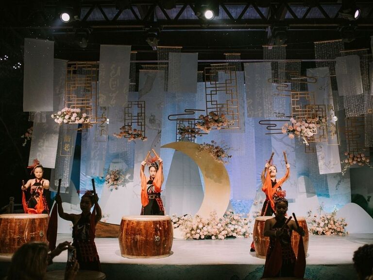 Drummers on stage with moon-inspired backdrop