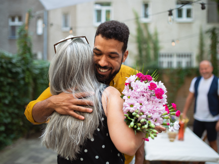 Son-in-law hugging mother-in-law with flowers