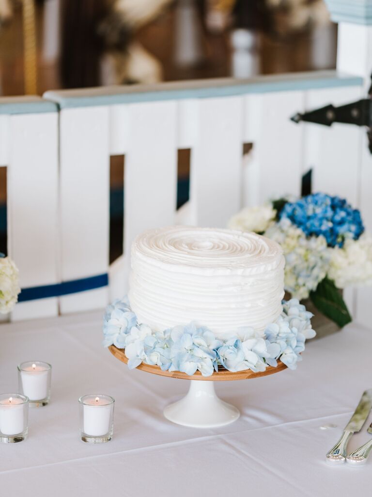 one tier buttercream wedding cake decorated with a circle of light blue hydrangeas