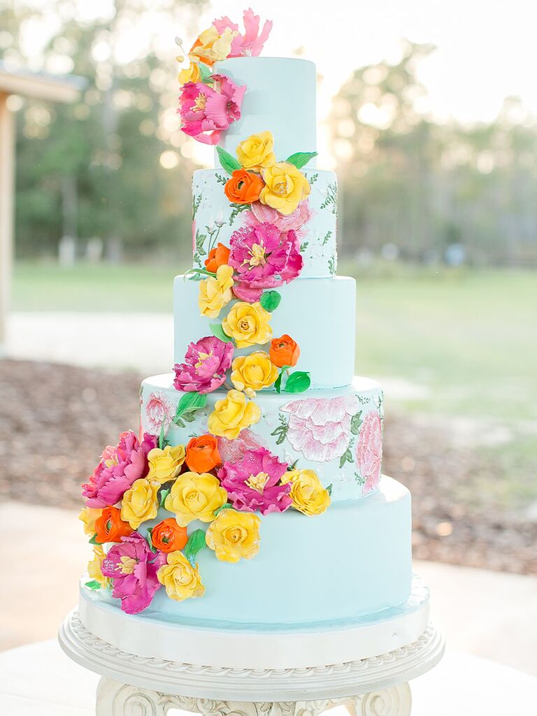 Vibrant blue spring wedding cake with pink, yellow, and orange flowers