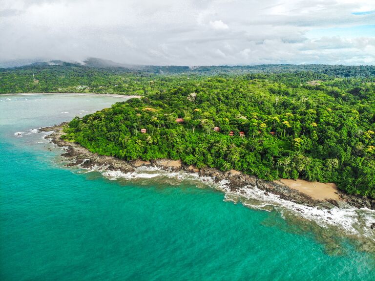 La Paloma Lodge aerial view of property with beautiful teal water and beautiful jungle rainforest