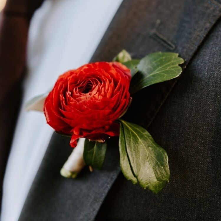 red ranunculus boutonniere on black suit lapel