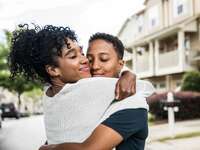 Lesbian couple embracing in front of home