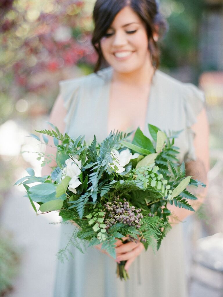 bridesmaid holding greenery bouquet with plumosa ferns, maidenhair ferns, lemon leaves, berries and white flowers
