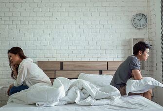 Couple sitting on opposite sides of the bed