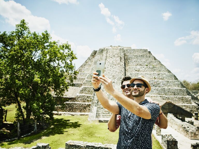 Smiling couple takes a selfie in front of the Mayan ruins of Belize. 